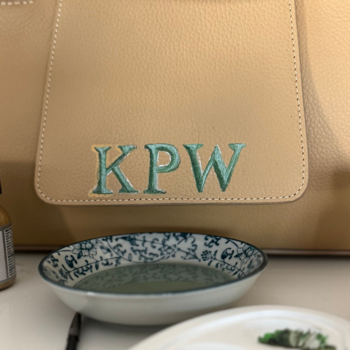 Actual hand-painted KPW initials on the front flap of a Canvas Sloane, with a paint palette below